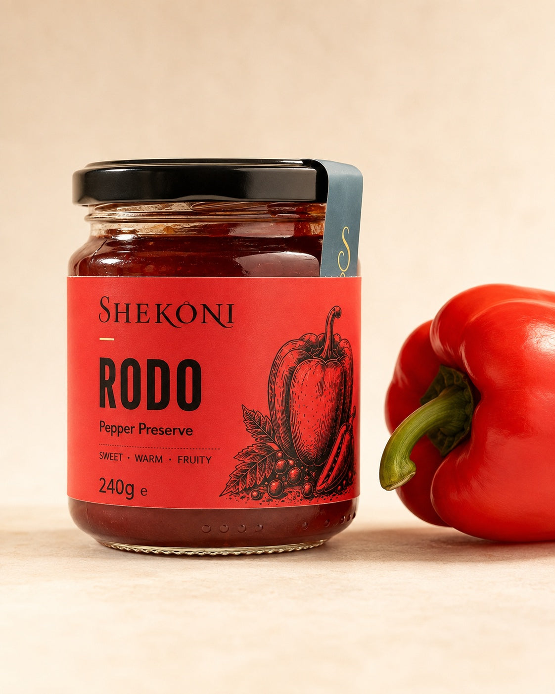 Shekoni sweet red pepper preserve jar beside a fresh red pepper