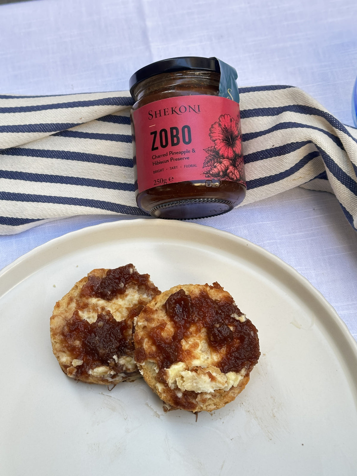 Zobo preserve spread over buttered scones on a cream plate